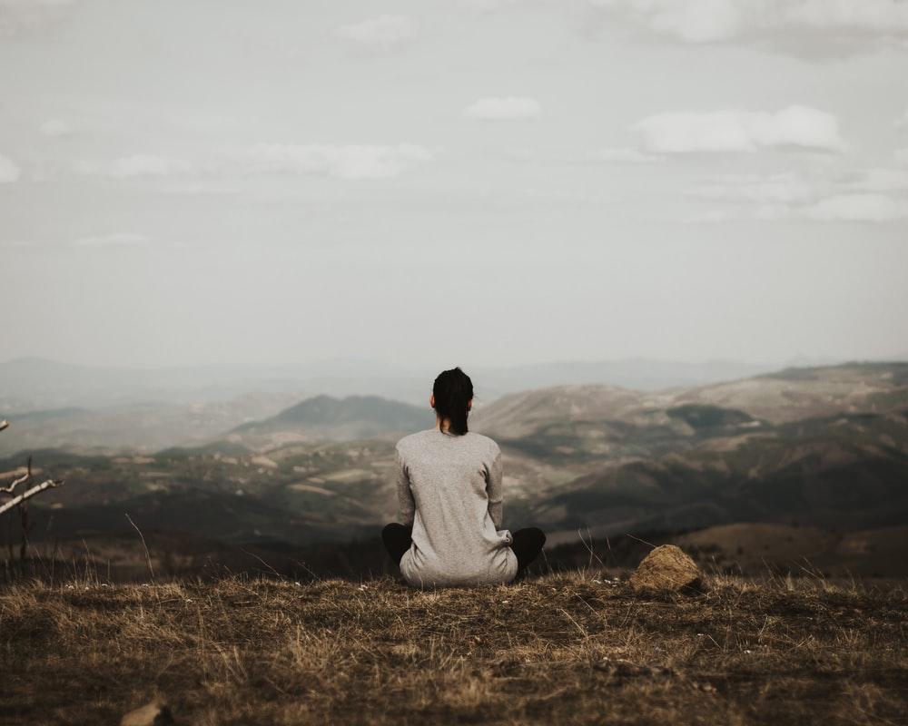 Person meditating on a hilltop.